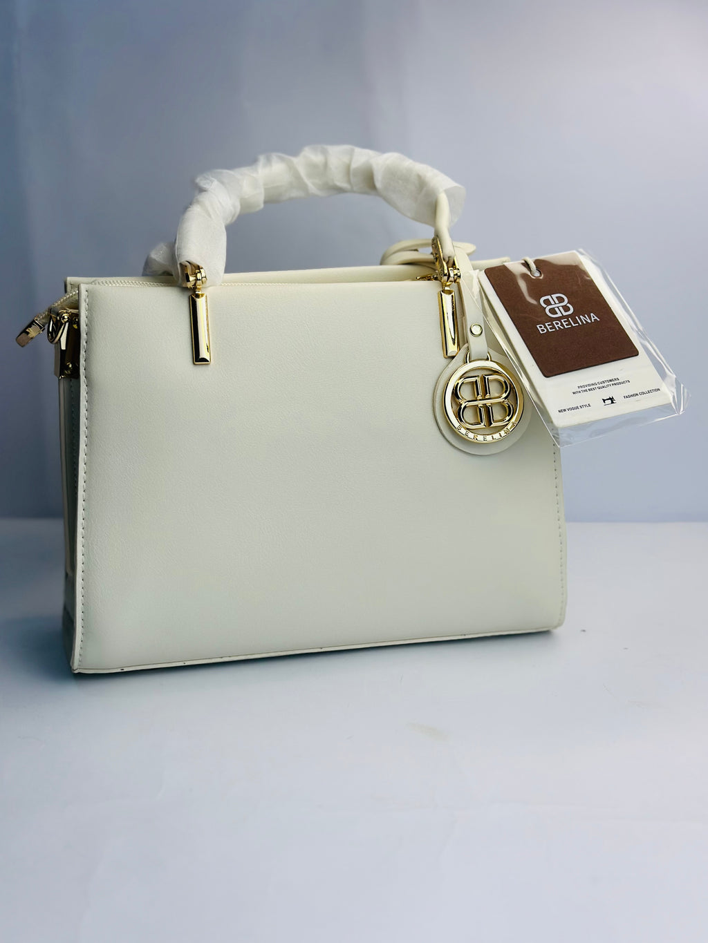 BERELINA SIGNATURE WHITE SATCHEL WITH GOLD EMBLEM DETAIL